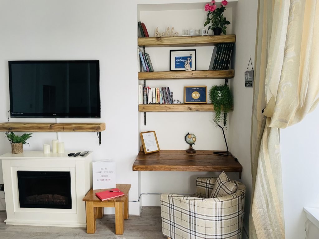 Living area with television, fireplace and workspace at King Street Holiday Apartment