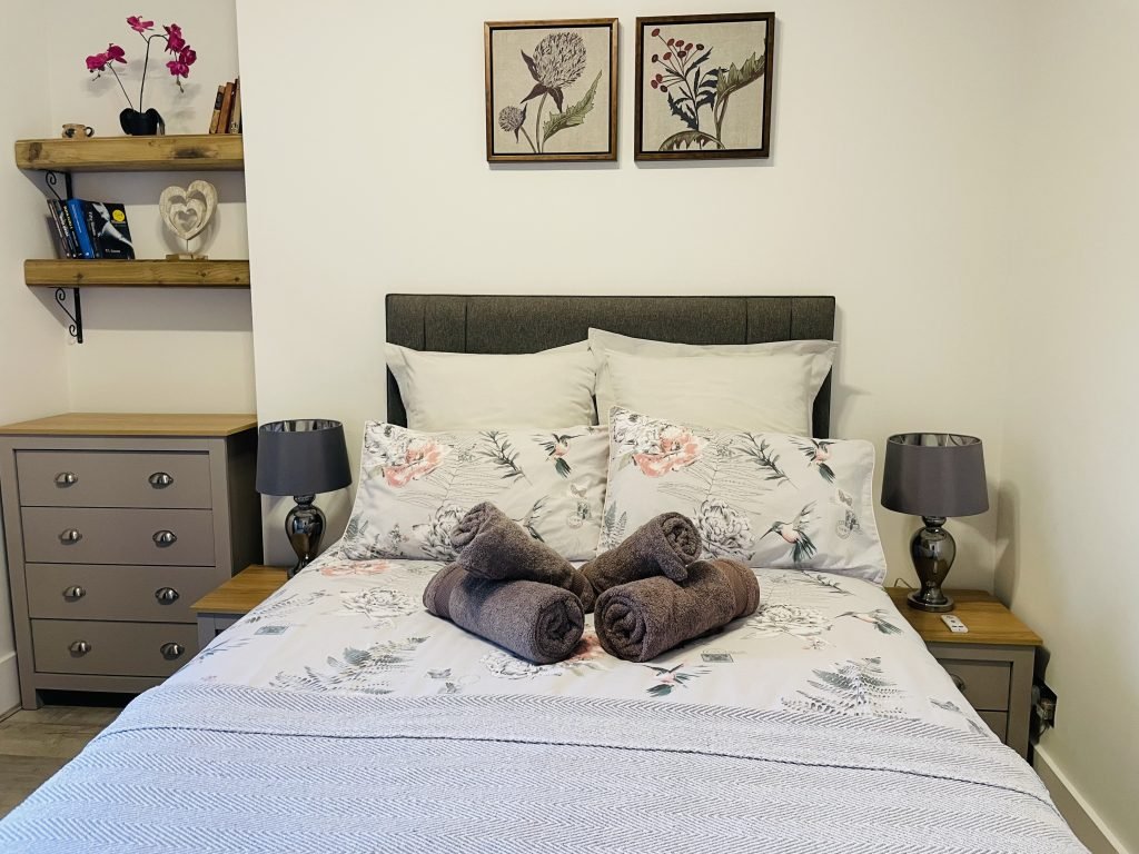Double bedroom with floral bedding and bedside lamps at King Street Holiday Apartment