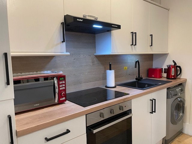 Kitchen with oven, hob, microwave and washing machine at King Street Holiday Apartment
