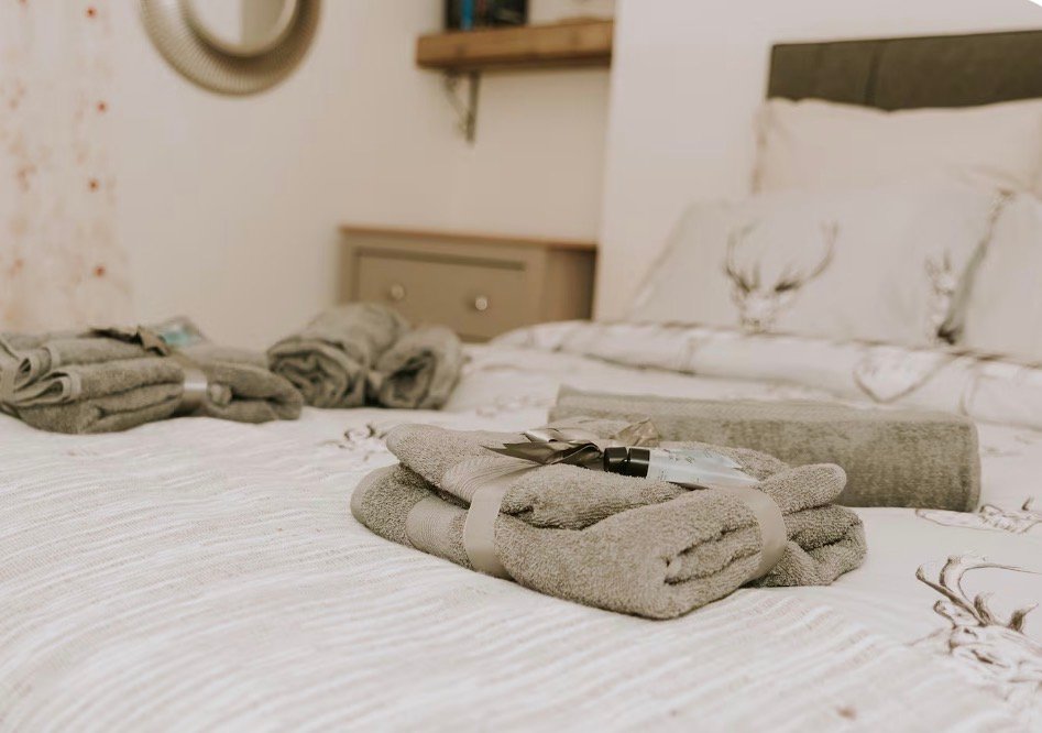 Folded welcome towels on the double bed with white bedding at King Street Holiday Apartment